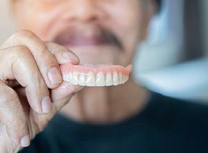 Man holding a full upper denture