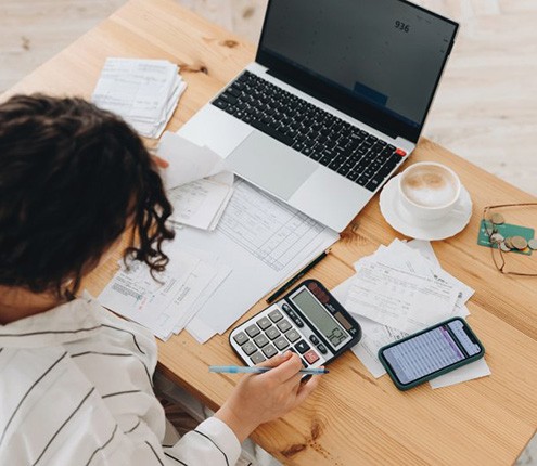 Woman at her desk bent over a calculator 