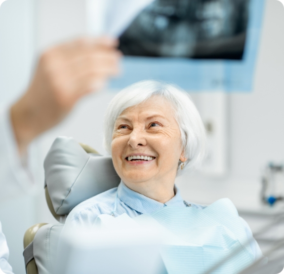 Older dental patient smiling up at dentist