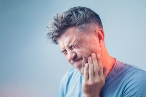 Man holding jaw in pain. 