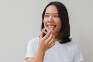 Woman smiling putting in her Invisalign while on a trip