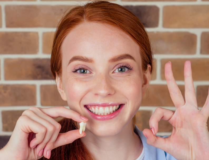 Smiling woman holding tooth