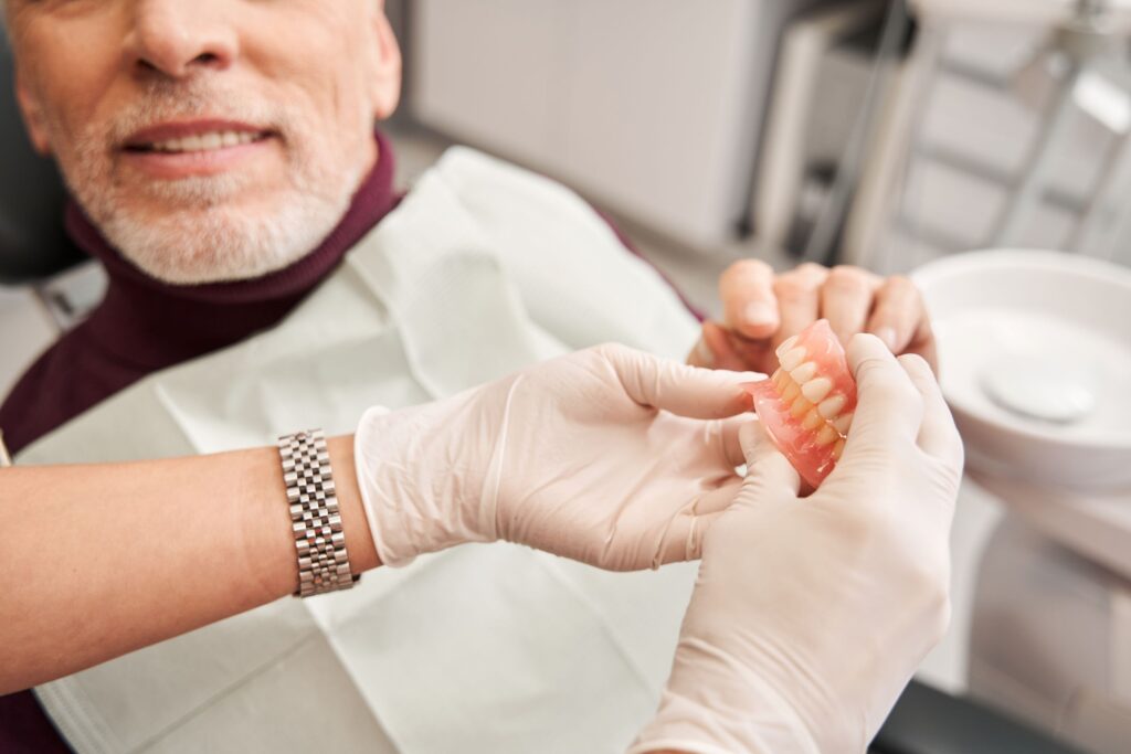 Man in dental chair receiving set of dentures