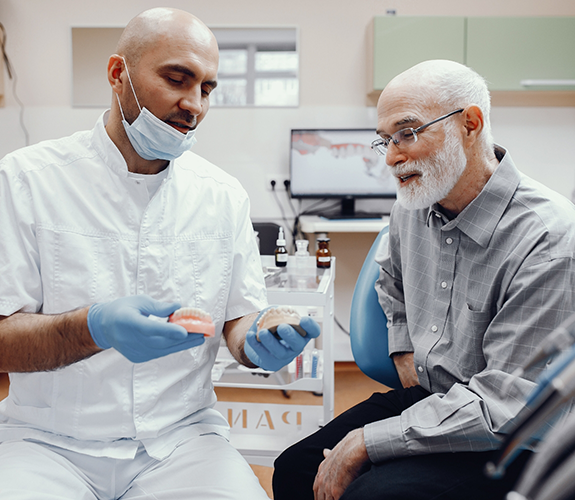 Dentist showing senior patient dentures in West Palm Beach