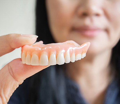 Close up of woman holding a full denture