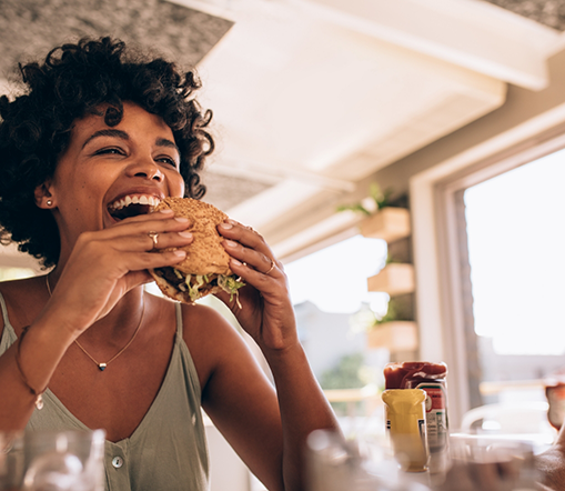 Woman sitting at table about to eat a burger